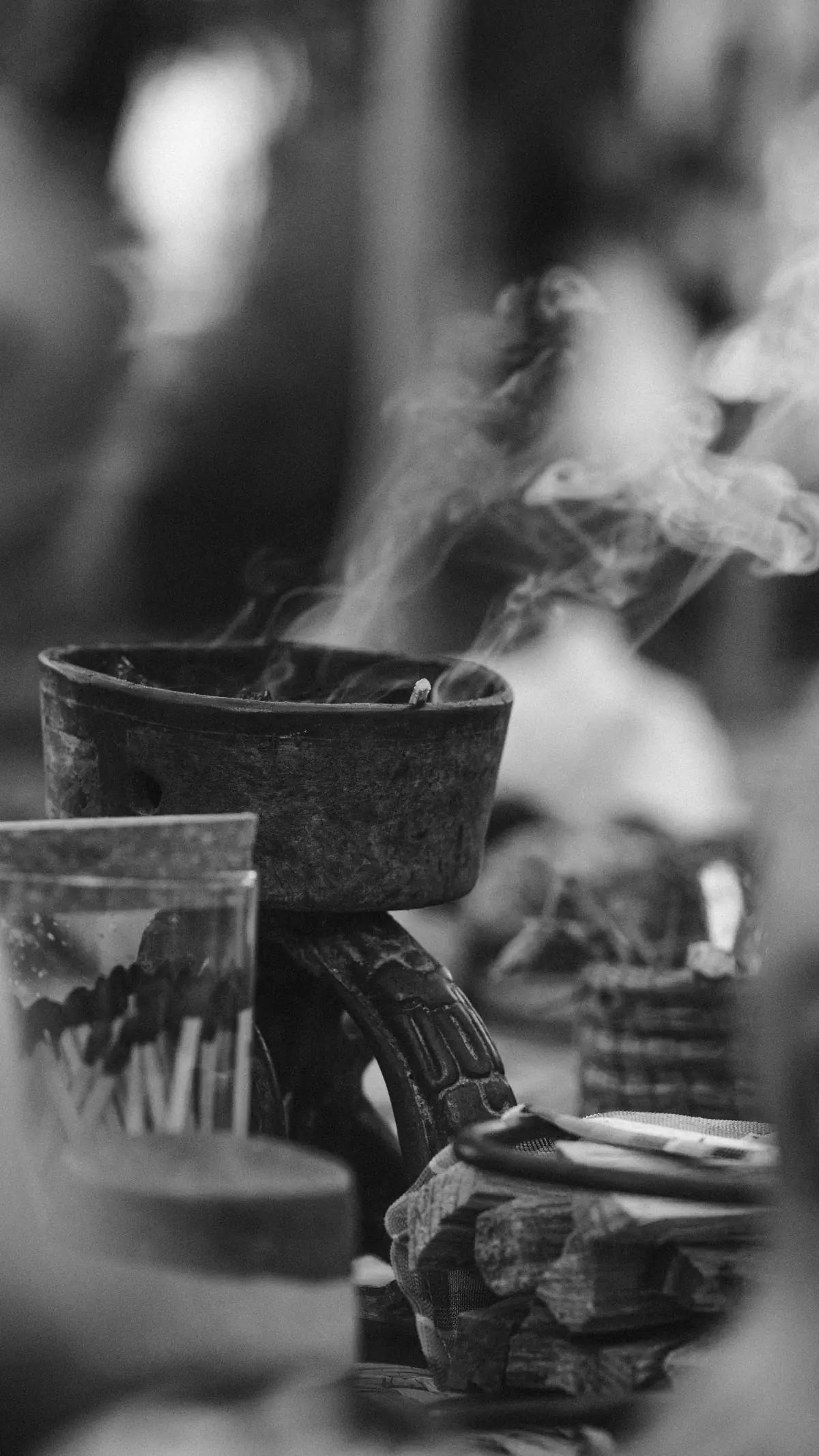 Black and white close-up of copal incense burning in a stone vessel, smoke rising