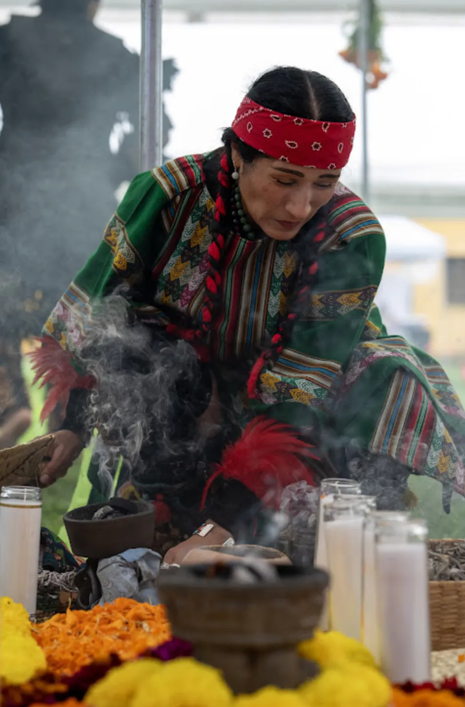 A Malintzin performs the sahumado, cleansing with copal smoke over candles and marigolds