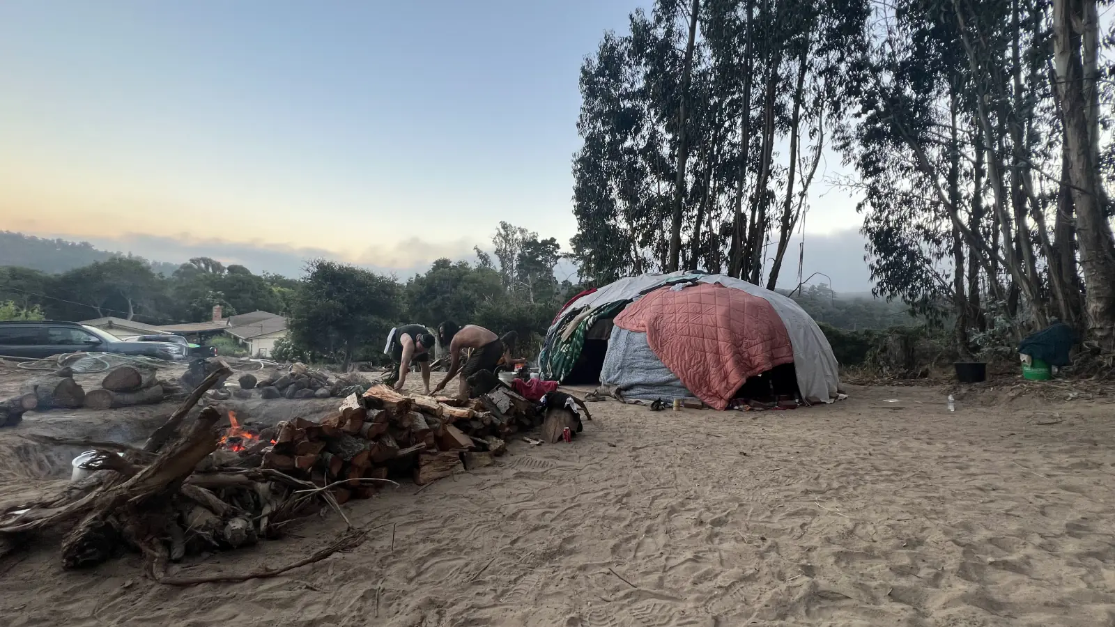 Volunteers tend the fire beside the temazcal structure at dusk